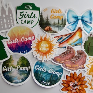 Pode incluir: Uma coleção de autocolantes coloridos com tema de acampamento. Os designs incluem um escudo verde com "Girls Camp 2026", um laço em aquarela, uma mochila, botas de caminhada e várias cenas da natureza. Alguns autocolantes apresentam o texto "Girls Camp 2026".