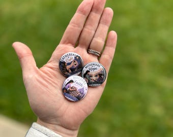 May include: Three round pinback buttons with different designs and text. One button says "Gatherers of Light" with a graphic of a person holding a lantern. Another says "Messengers of Hope" with a graphic of two people. The third says "Builders of Faith" with a graphic of a person.