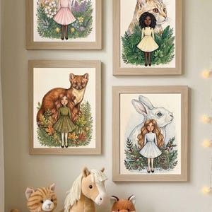 Pode incluir: Quatro quadros de parede com ilustrações de crianças e animais em ambientes naturais, incluindo um cavalo, um gato, uma raposa e um coelho, exibidos sobre três peluches: um gato tigrado, um cavalo e uma raposa.