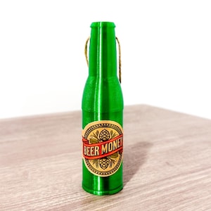 Puede incluir: Una botella de vidrio verde con una etiqueta que dice "Beer Money". La botella tiene un lazo de cuerda en la parte superior.