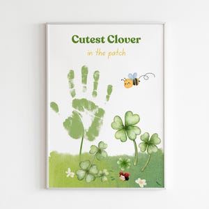May include: A green handprint on a white background with the text "Cutest Clover in the patch". The handprint is surrounded by green clover leaves and a small bee.