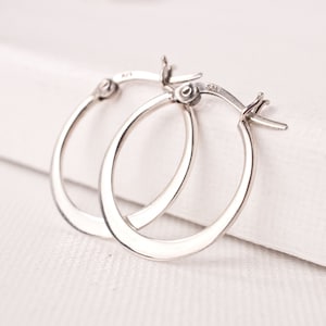 May include: A pair of silver hoop earrings. The earrings are simple and elegant, with a smooth, polished finish.
