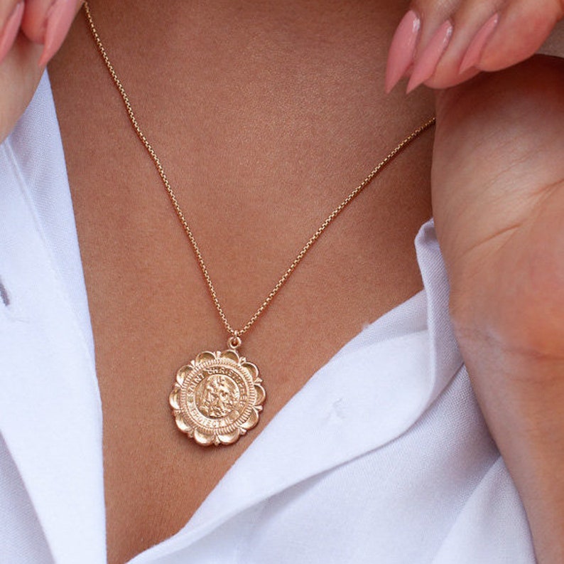 Peut inclure: Un collier en cha&icirc;ne dor&eacute;e avec un grand pendentif circulaire orn&eacute;. Le pendentif pr&eacute;sente un design d&eacute;taill&eacute; et une surface textur&eacute;e.