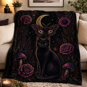 May include: A black blanket featuring a black cat, a crescent moon, a moth, mushrooms, and purple roses against a starry night background. The blanket is draped over a beige sofa, creating a cozy and mystical aesthetic.