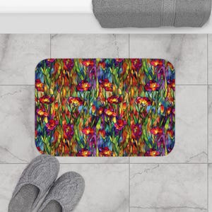 Könnte beinhalten: Eine rechteckige Badematte mit einem farbenfrohen Blumenmuster. Die Matte hat einen Buntglaseffekt mit roten, gelben, orangefarbenen, grünen und violetten Blumen und Blättern. Die Matte liegt auf einem gefliesten Boden, mit grauen Hausschuhen.