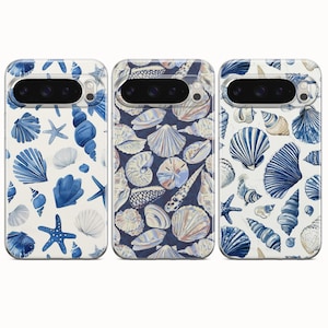 May include: Three phone cases with seashell designs. The cases feature various blue and white seashell illustrations on a white and navy blue background. The cases have a glossy finish and are designed to fit a smartphone.