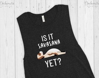 Può includere: Canotta grigio scuro con la scritta "IS IT SAVASANA YET?" e l'illustrazione di un cane nella posizione Savasana. La canotta senza maniche ha lo scollo tondo. Il testo è bianco.
