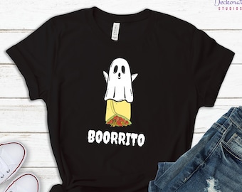 May include: Black t-shirt featuring a white ghost design over a burrito. The word "BOORRITO" is printed in white below the graphic. The shirt is displayed with blue jeans and white sneakers on a light wood surface.