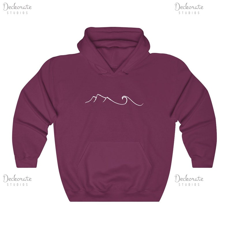 May include: Burgundy hoodie with a white mountain and wave design. The sweatshirt has a front pocket and a hood. The text "Deckorate Studios" is printed in white on the top right and bottom left corners.