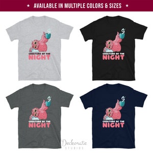 May include: Four t-shirts in different colors: gray, black, charcoal, and navy blue. Each shirt features a pink owl graphic holding a mug with steam, and the text "CREATURE OF THE NIGHT" in pink and white.