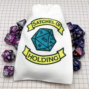May include: A white canvas dice bag with the text "SATCHEL OF HOLDING" and a blue and black twenty-sided die graphic. Assorted polyhedral dice in purple, black, and blue surround the bag, perfect for tabletop gaming.