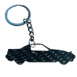 May include: A black and silver car keychain with a carbon fiber pattern. The keychain is attached to a silver key ring and chain.