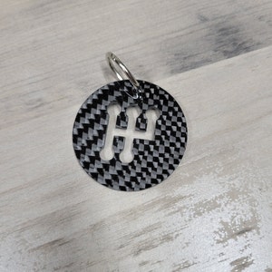 May include: A black carbon fibre keychain with a cut-out gear shift pattern.
