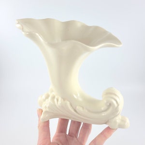 May include: A white ceramic vase with a trumpet-shaped opening and a decorative, swirling base.