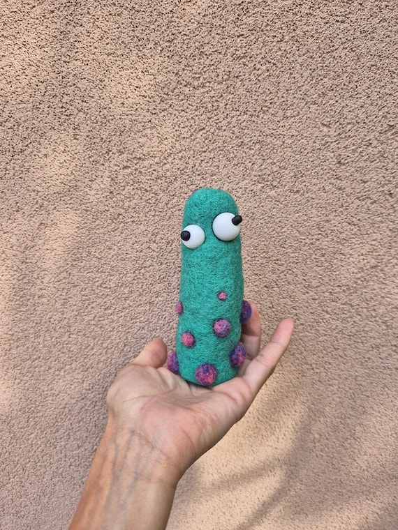 A chubby green spotted creature hand-sculpted from wool fiber — the kind of weird little desk companion that sparks a 'where did you get THAT?' every single time.