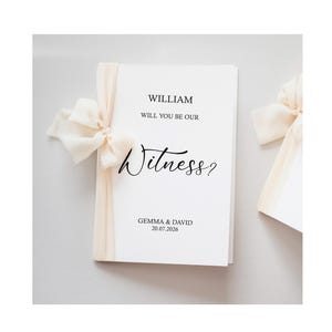 Puede incluir: Una tarjeta blanca con el texto "WILLIAM WILL YOU BE OUR Witness?" atada con una cinta color crema. Los nombres "GEMMA & DAVID" y la fecha "20.07.2026" están impresos en la parte inferior.