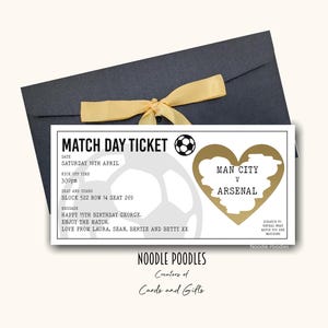 Pode incluir: Um bilhete de jogo de futebol para o jogo Man City vs Arsenal, apresentado num envelope azul escuro com uma fita dourada. O bilhete inclui a data, hora e detalhes do assento.