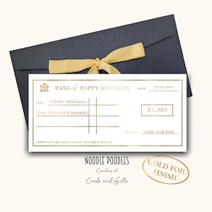May include: A birthday cheque design with gold foil detailing, presented with a navy envelope and a gold ribbon. The cheque is made out to Adam Williams for £1,000, signed by Mom and Dad.