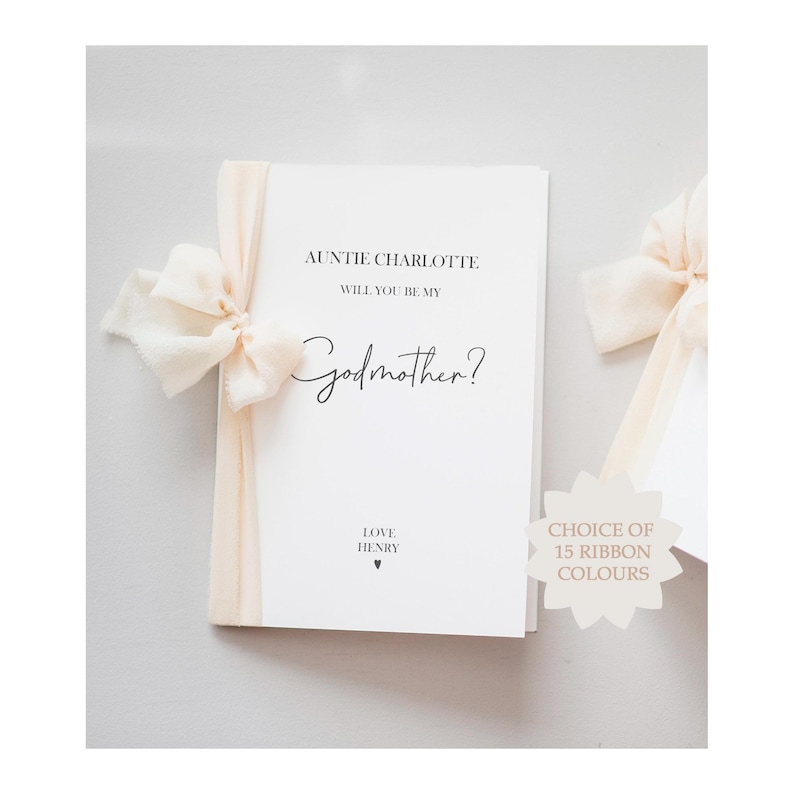 A white card with a peach ribbon tied around it reads, "AUNTIE CHARLOTTE WILL YOU BE MY Godmother? LOVE HENRY" with a small heart.