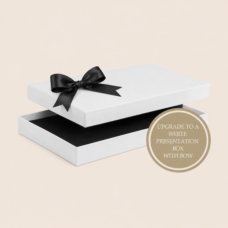A white presentation box with a black interior and a black ribbon tied in a bow on the lid.