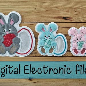May include: Four embroidered bunny rabbit patches with an egg in their paws. The bunnies are gray, blue, pink, and brown. The patches are on a wooden background. The text "Digital Electronic File" is below the patches.