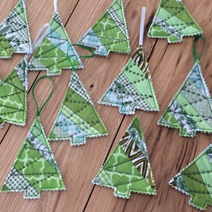 Puede incluir: Una colección de 12 adornos de árbol de Navidad de tela patchwork verde y blanca con un borde festoneado blanco y costuras verdes. Los adornos están colgados de una cuerda blanca.