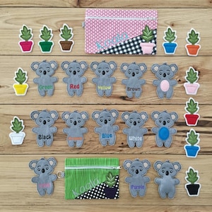 May include: A set of felt koala finger puppets with matching colour pots and plants. The koalas are labelled with different colours: green, red, yellow, brown, black, orange, blue, white, pink, and purple. The pots and plants are also labelled with the same colours.