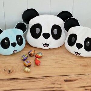 May include: Five plush panda head toys in different sizes and colors. The largest panda is white with black eyes and a black nose. The second largest panda is light blue with black eyes and a black nose. The third largest panda is white with black eyes and a black nose. The fourth largest panda is white with black eyes and a black nose. The smallest panda is white with black eyes and a black nose. The pandas are all smiling.