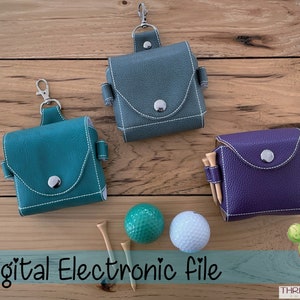 Könnte beinhalten: Drei kleine, quadratische Golfaccessoires in Teal, Grau und Lila, jeweils mit einem silbernen Verschluss und weißen Nähten. Zwei Golfbälle und Tees sind ebenfalls vorhanden. Der Text "Digital Electronic File" befindet sich unten.
