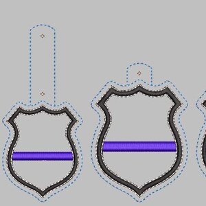 K&ouml;nnte beinhalten: Vier verschiedene Gr&ouml;&szlig;en von schwarzen und wei&szlig;en Polizeibadgen-Umrandungen mit einem violetten Streifen in der Mitte. Die Abzeichen sind f&uuml;r die Stickerei.