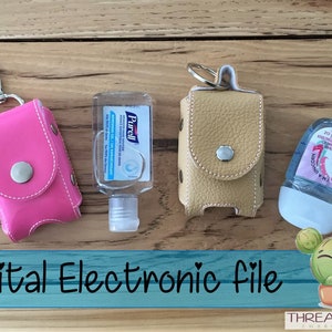May include: Three leather hand sanitizer holders with keychains. The holders are pink, yellow, and brown. The holders are on a wooden surface with a small cactus illustration and the text "Digital Electronic File" and "THREADMODE EMBROIDERY".