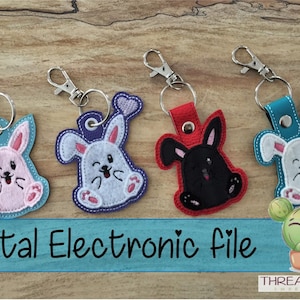 May include: Four embroidered bunny keychains with different colored felt and a heart detail. The keychains are on a wooden surface with a small cactus illustration and the text "Digital Electronic File".
