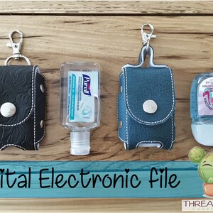 May include: Three hand sanitizer holders made of black and blue leather with white stitching. Each holder has a silver metal clasp and a silver metal button. The holders are displayed on a wooden surface with bottles of hand sanitizer.