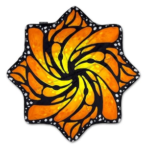 Könnte beinhalten: Eine sternförmige Decke mit einem lebendigen Monarchfalter-Flügelmuster in Orange-, Gelb- und Schwarztönen. Das Design zeigt eine wirbelnde, radiale Anordnung von Flügelsegmenten mit weißen Punkten entlang der schwarzen Außenränder.