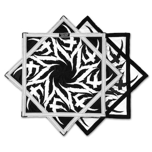 May include: Black and white star-shaped decorative textile with a central swirling design. The textile has a white border with a stitched pattern. The text "FIRST EARTH FLON STAR" is visible on a small label.