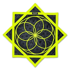 May include: A star-shaped fabric item with a black background featuring a repeating geometric pattern and a bright neon yellow border. A central neon yellow circular geometric design is stitched on top. A small black label reads FIRST EARTH FLOW STAR.