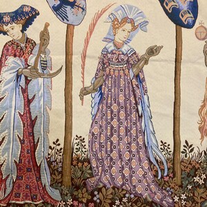 May include: A tapestry depicting three figures in a garden setting. The figures are dressed in medieval clothing and are standing near trees. The tapestry is woven with intricate details and vibrant colors, including shades of blue, red, green, and gold.