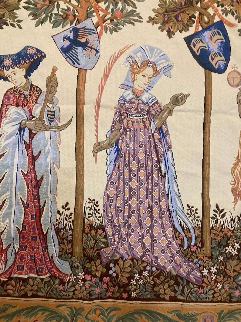 May include: A tapestry depicting three figures in a garden setting. The figures are dressed in medieval clothing and are standing near trees. The tapestry is woven with intricate details and vibrant colors, including shades of blue, red, green, and gold.