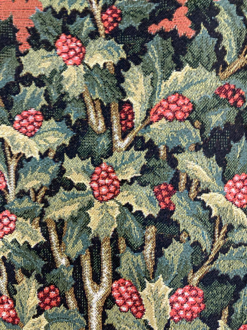 Op de afbeelding: Close-up van een tapijtstof met een herhalend patroon van groene bladeren en rode bessen. De stof heeft een textuur en is geweven.