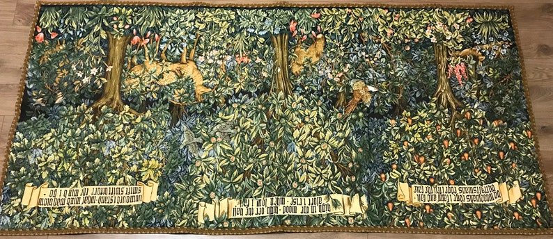 May include: A tapestry depicting a forest scene with a variety of trees, flowers, and animals. The tapestry is woven with intricate details and vibrant colors. The text on the tapestry reads: " -  Of  I  am  my  Lord  am  I  mine  mine  own  good  Lord  ever  I  shall  be  - "