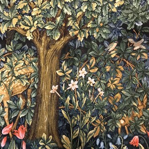 May include: A tapestry depicting a forest scene with a large tree, deer, and various flowers and plants. The tapestry features a dark blue background with shades of green, brown, and white.