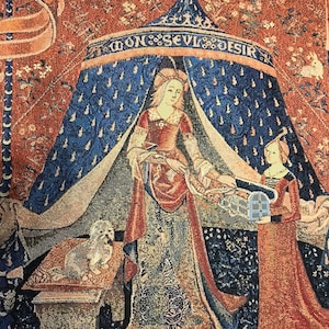 May include: A tapestry depicting a woman in a blue and red robe standing under a canopy with the words 'Mon Seul Desir' above. The woman is holding a small bird in her hand. A second woman in a red robe stands to the right of the canopy. A small white dog sits on a stone pedestal to the left of the canopy.