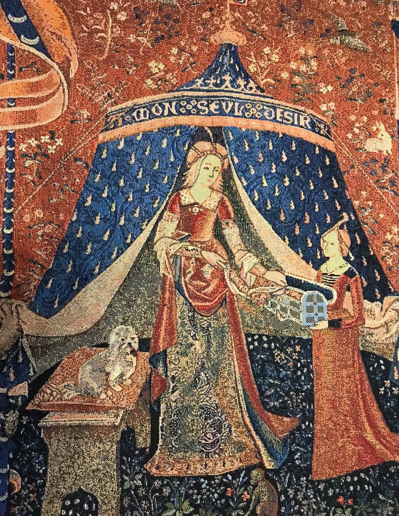 May include: A tapestry depicting a woman in a blue and red robe standing under a canopy with the words 'Mon Seul Desir' above. The woman is holding a small bird in her hand. A second woman in a red robe stands to the right of the canopy. A small white dog sits on a stone pedestal to the left of the canopy.