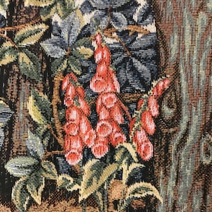 May include: Close-up of a tapestry featuring a floral design with red, green, and blue flowers. The flowers are woven into the fabric and have a textured appearance.