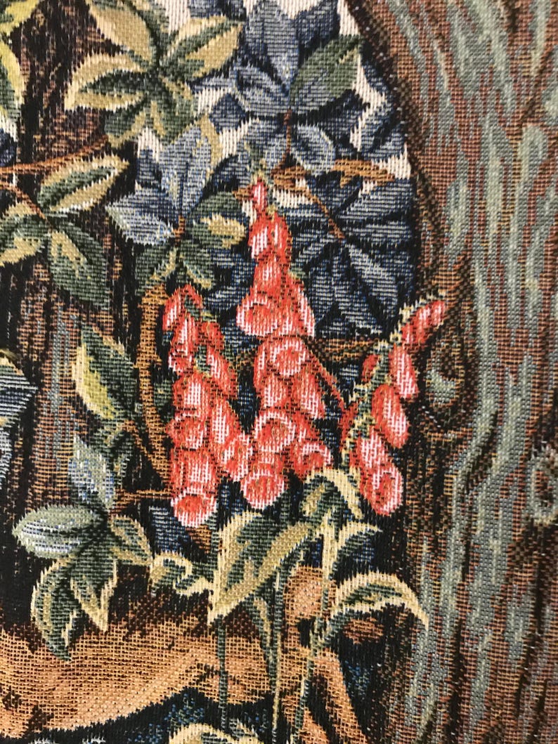 May include: Close-up of a tapestry featuring a floral design with red, green, and blue flowers. The flowers are woven into the fabric and have a textured appearance.
