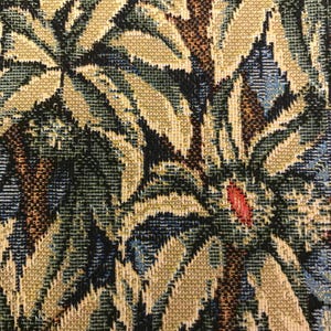 May include: Close-up of a tapestry fabric with a repeating pattern of green, brown, and blue leaves. The leaves are woven into the fabric and have a textured appearance.