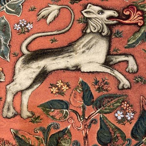 May include: A white tapestry with a stylized lion with a red flame coming out of its mouth. The lion is surrounded by green and orange floral designs.