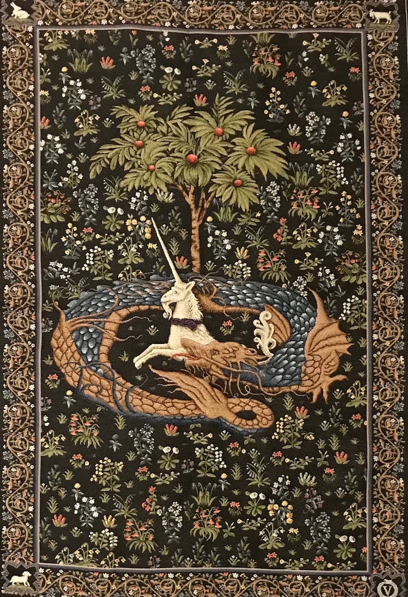 Op de afbeelding: Een wandkleed met een wit eenhoorn met een gouden hoorn, gevangen in de kronkels van een blauwe en bruine draak. De sc&egrave;ne speelt zich af tegen een donkergroene achtergrond met verschillende bloemen en een kleine groene boom.