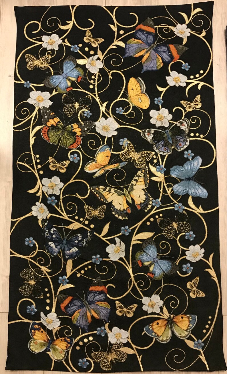 May include: Black tapestry featuring a repeating pattern of gold swirls and butterflies in various colors, including yellow, blue, and orange. The butterflies are surrounded by small white flowers.