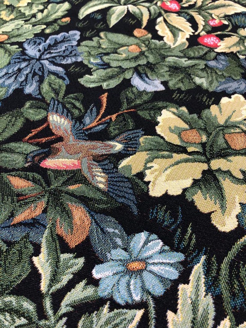 May include: A black tapestry fabric with a floral pattern featuring birds, leaves, and flowers in shades of green, blue, brown, and yellow.